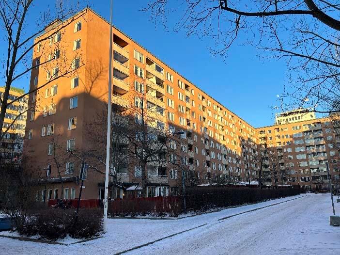 Flerbostadshus i Stockholm med tegelfasad och balkonger under vintertid, fotograferat i samband med fönsterrenovering i en bostadsrättsförening.