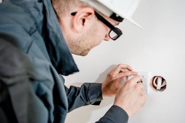 Elektriker som installerar och monterar ett uttag i en bostad.